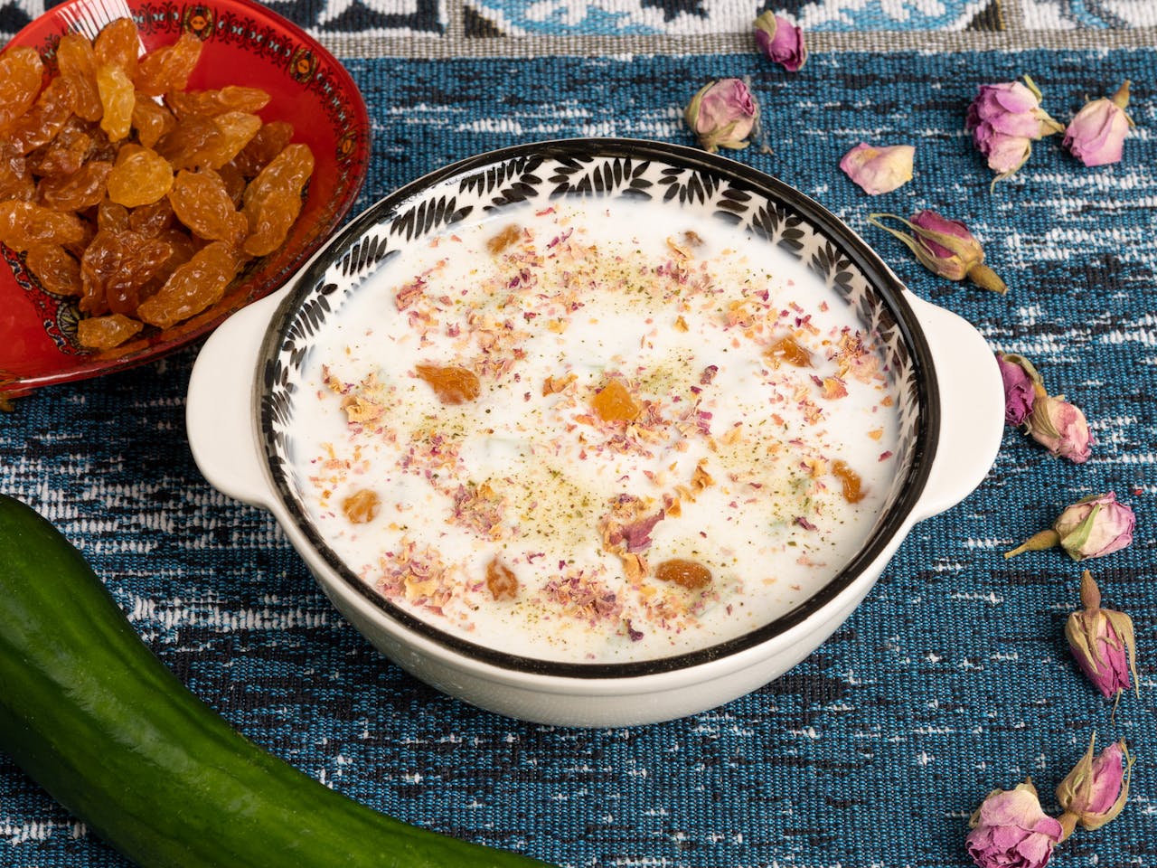 A vibrant yogurt dish garnished with raisins and herbs, served on a traditional cloth.